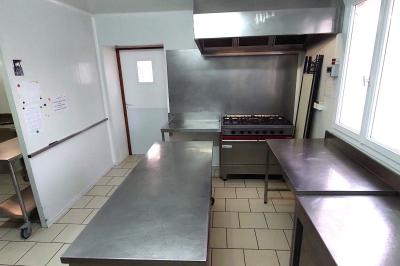 Table de tennis de table bleue en extérieur, avec deux raquettes rouges posées de part et d'autre du filet.