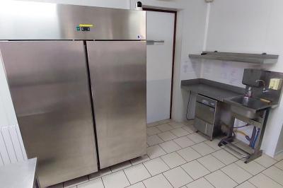 Table de tennis de table bleue en extérieur, avec deux raquettes rouges posées de part et d'autre du filet.