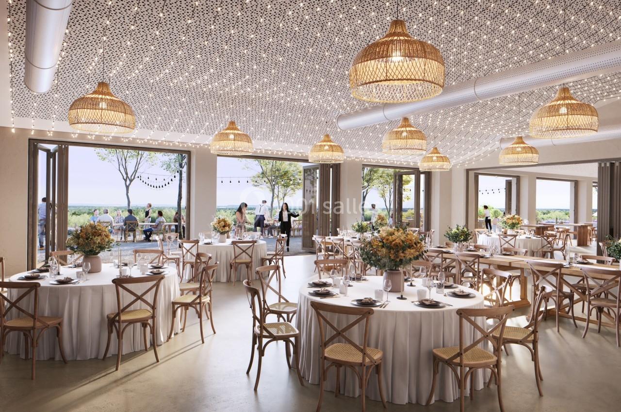 Salle de réception lumineuse avec tables rondes décorées, chaises en bois et grandes baies vitrées ouvertes sur une terrasse.
