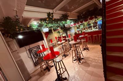 Miniature Location salle Paris 6 (Paris) - Bodega Saint Germain #2 Façade d'un restaurant à l'éclairage rouge vif, avec une entrée ouverte et des décorations florales au-dessus.