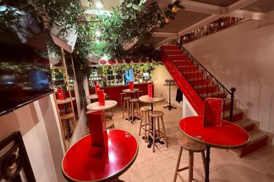 Miniature Location salle Paris 6 (Paris) - Bodega Saint Germain #1 Façade d'un restaurant à l'éclairage rouge vif, avec une entrée ouverte et des décorations florales au-dessus.