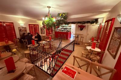 Miniature Location salle Paris 6 (Paris) - Bodega Saint Germain #3 Façade d'un restaurant à l'éclairage rouge vif, avec une entrée ouverte et des décorations florales au-dessus.