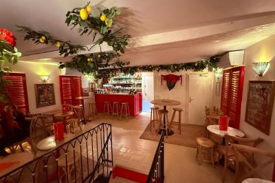 Miniature Location salle Paris 6 (Paris) - Bodega Saint Germain #4 Façade d'un restaurant à l'éclairage rouge vif, avec une entrée ouverte et des décorations florales au-dessus.