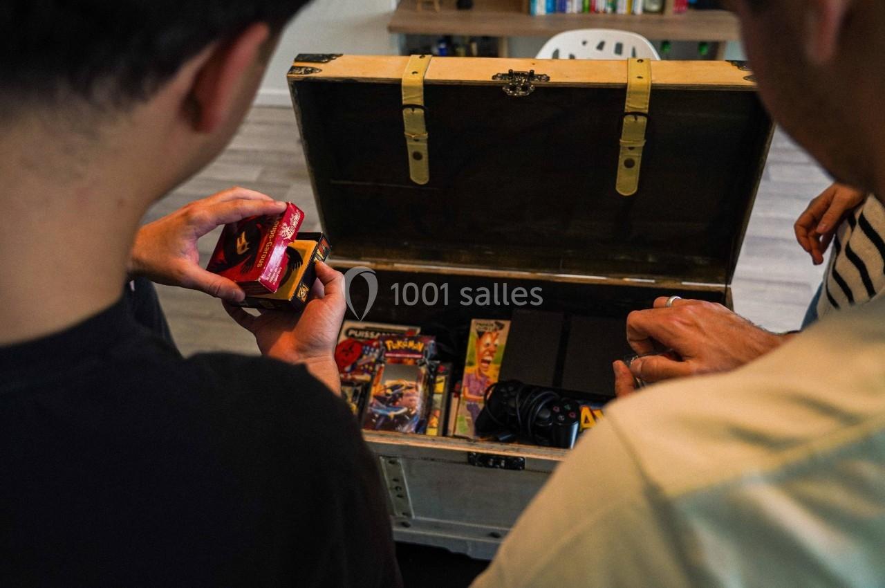 Deux personnes ouvrent un coffre contenant des jeux vidéo rétro, des manettes et des accessoires.