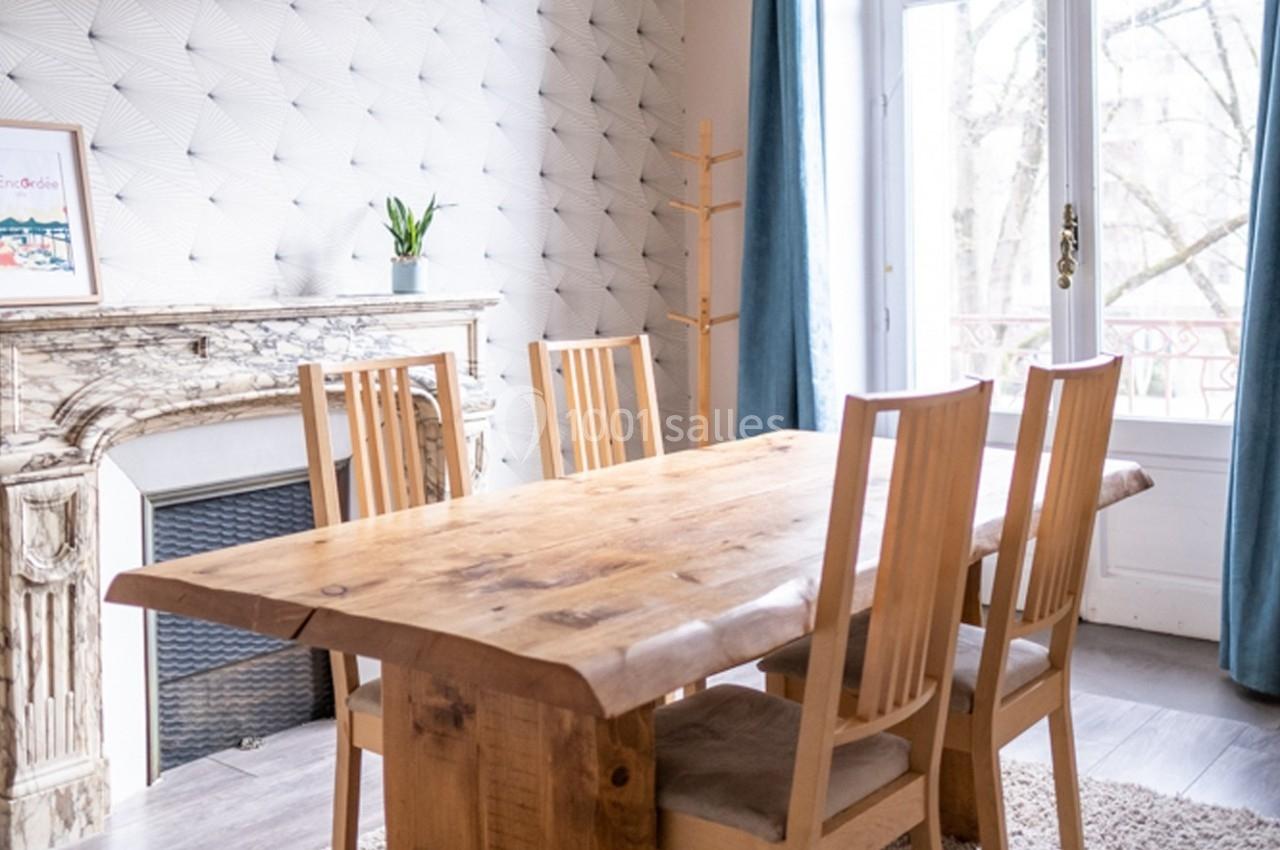 Salle à manger lumineuse avec une table en bois massif, quatre chaises assorties et une cheminée en marbre.