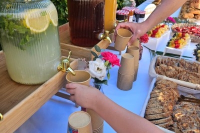 Miniature Traiteur Villefranche-sur-Saône (Rhône) - Delicesbykam #2 Buffet décoré avec des fleurs, fruits frais, verrines, mini-burgers et desserts, présenté sur une table élégante.