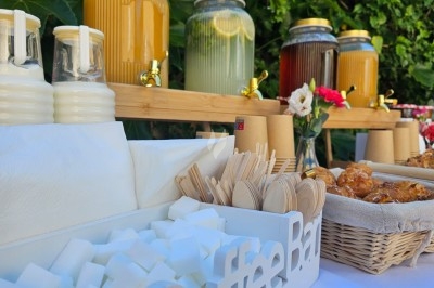 Miniature Traiteur Villefranche-sur-Saône (Rhône) - Delicesbykam #3 Buffet décoré avec des fleurs, fruits frais, verrines, mini-burgers et desserts, présenté sur une table élégante.