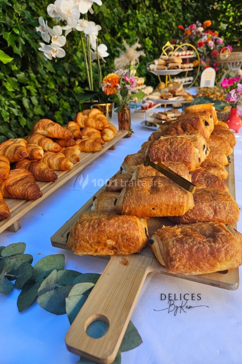 Plateau de viennoiseries comprenant pains au chocolat et croissants, disposé sur une table décorée de fleurs.