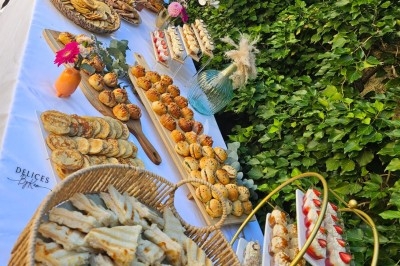 Miniature Traiteur Villefranche-sur-Saône (Rhône) - Delicesbykam #5 Buffet décoré avec des fleurs, fruits frais, verrines, mini-burgers et desserts, présenté sur une table élégante.