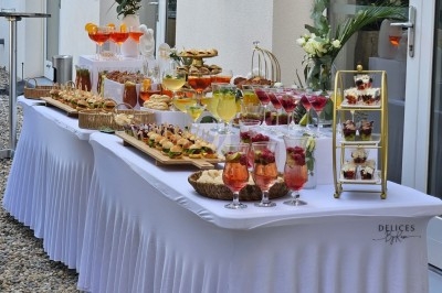 Miniature Traiteur Villefranche-sur-Saône (Rhône) - Delicesbykam #11 Buffet décoré avec des fleurs, fruits frais, verrines, mini-burgers et desserts, présenté sur une table élégante.