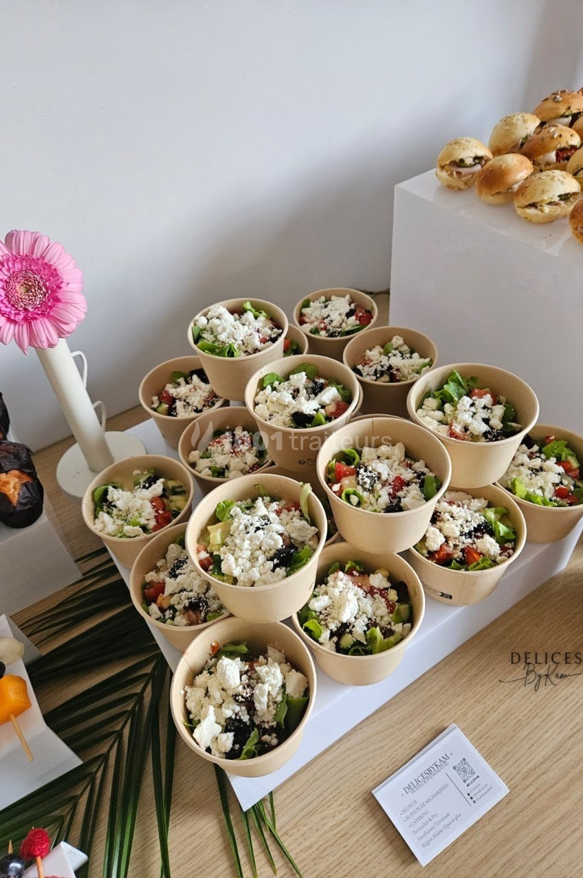 Salades colorées en portions individuelles dans des bols en carton, accompagnées de mini-burgers et brochettes de fruits.