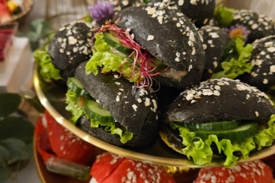 Miniature Traiteur Villefranche-sur-Saône (Rhône) - Delicesbykam #21 Buffet décoré avec des fleurs, fruits frais, verrines, mini-burgers et desserts, présenté sur une table élégante.