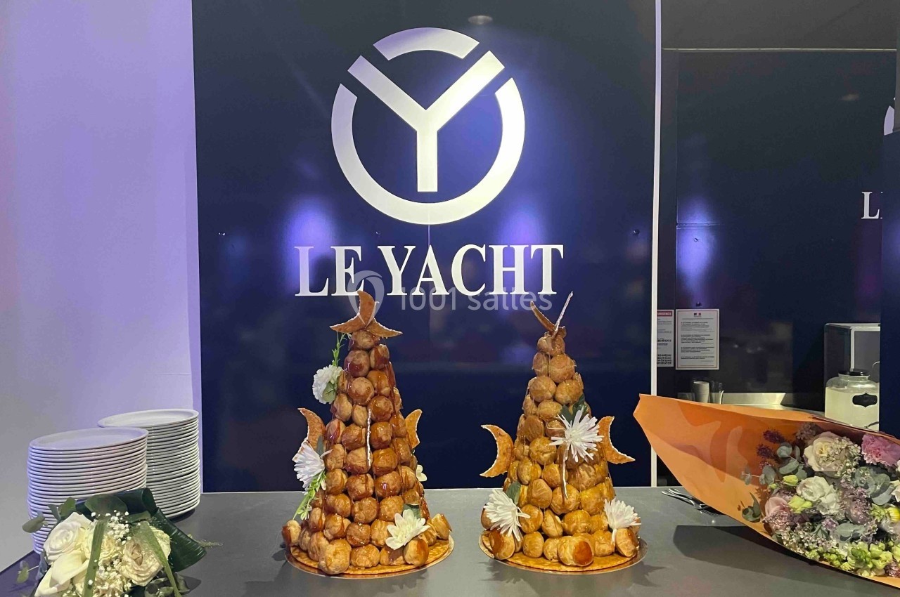 Deux pièces montées en choux décorées de fleurs et étoiles, posées sur un comptoir devant un logo ’Le Yacht’.