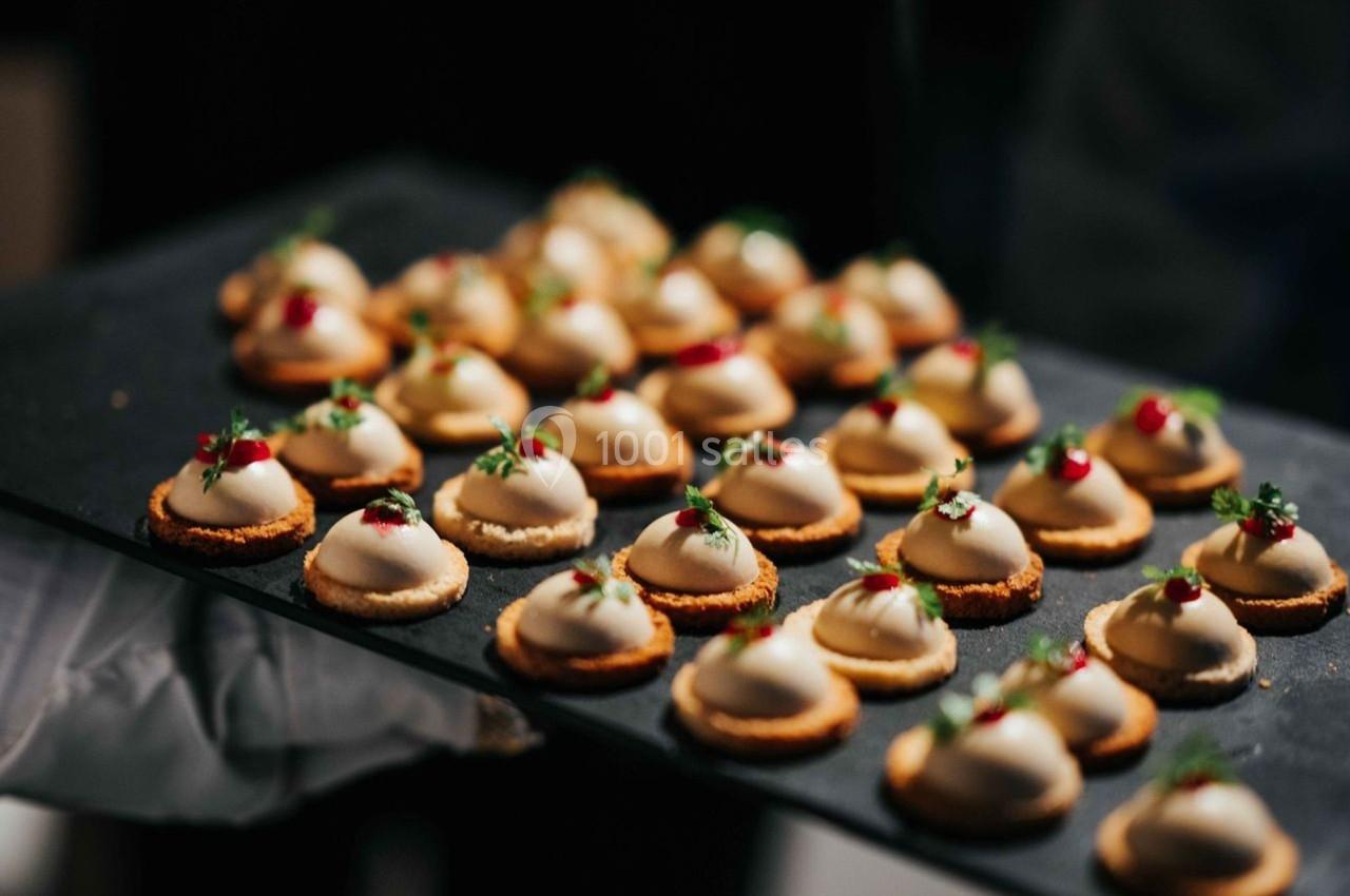 Plateau de bouchées apéritives garnies de mousse et décorées de petites herbes et baies rouges.