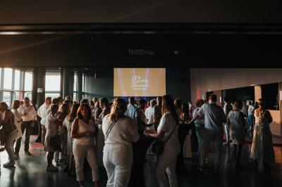 Rangées de chaises noires alignées dans une salle lumineuse avec une table en bois au premier plan.