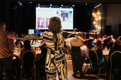 Rangées de chaises noires alignées dans une salle lumineuse avec une table en bois au premier plan.