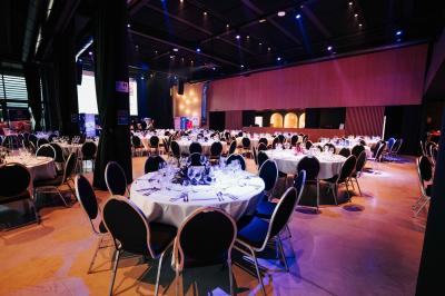 Rangées de chaises noires alignées dans une salle lumineuse avec une table en bois au premier plan.