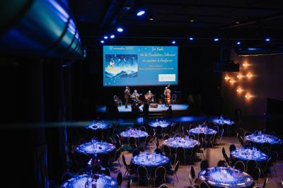 Rangées de chaises noires alignées dans une salle lumineuse avec une table en bois au premier plan.