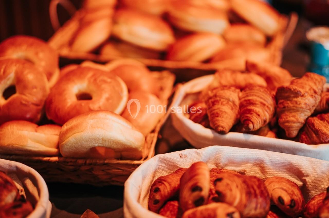 Paniers remplis de croissants, pains au chocolat et bagels disposés sur une table.