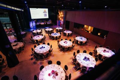 Rangées de chaises noires alignées dans une salle lumineuse avec une table en bois au premier plan.