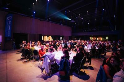 Rangées de chaises noires alignées dans une salle lumineuse avec une table en bois au premier plan.