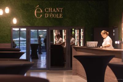 Terrasse moderne avec tables et parasols, entourée de pelouse, sous un ciel bleu dégagé.