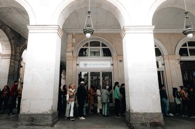 Bouteilles de bière variées alignées sur une étagère en bois devant un mur en pierre.
