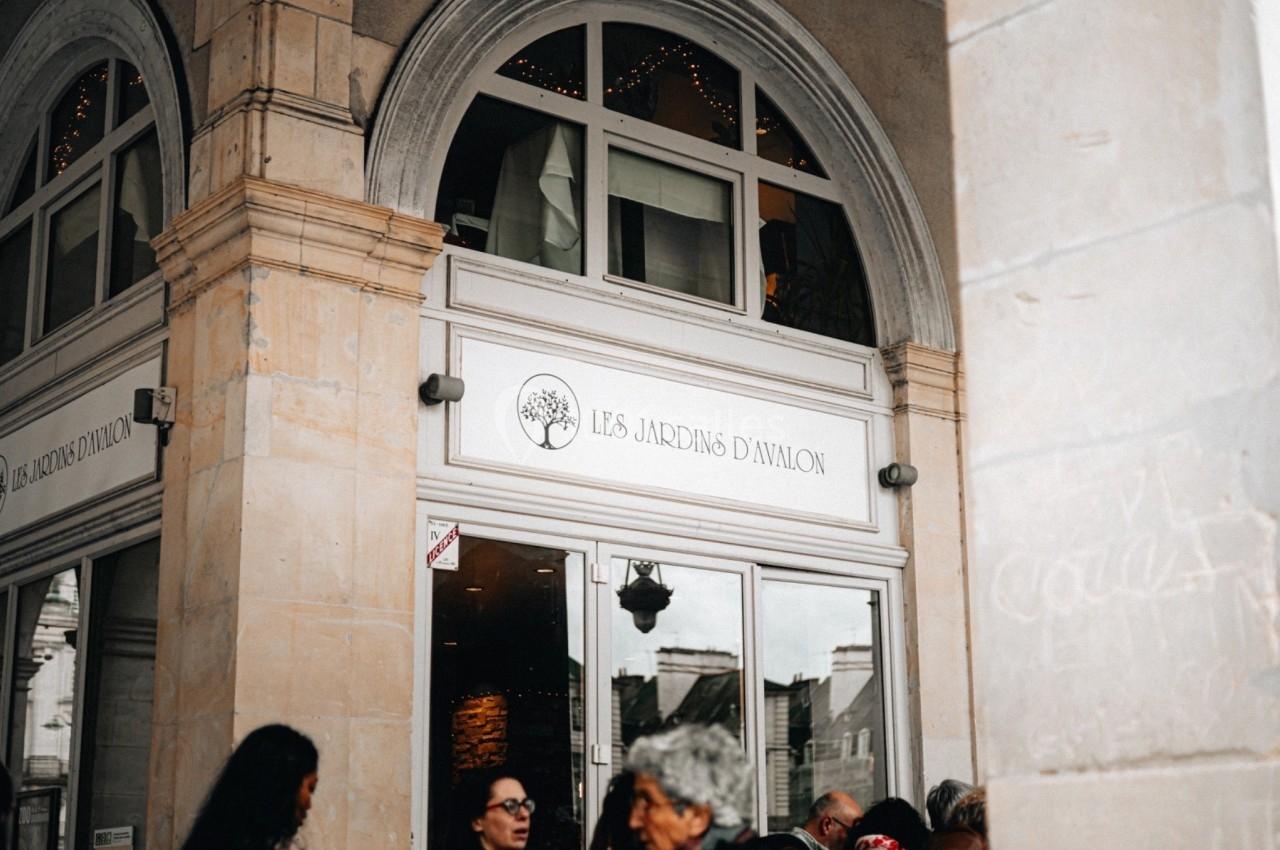 Façade d'un restaurant nommé ’Les Jardins d'Avalon’ avec des arches en pierre et une entrée vitrée.