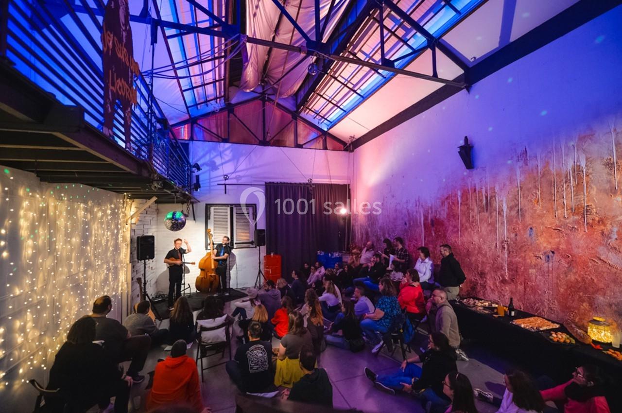 Un groupe joue de la musique devant un public assis dans une salle avec éclairage coloré et décorations lumineuses.