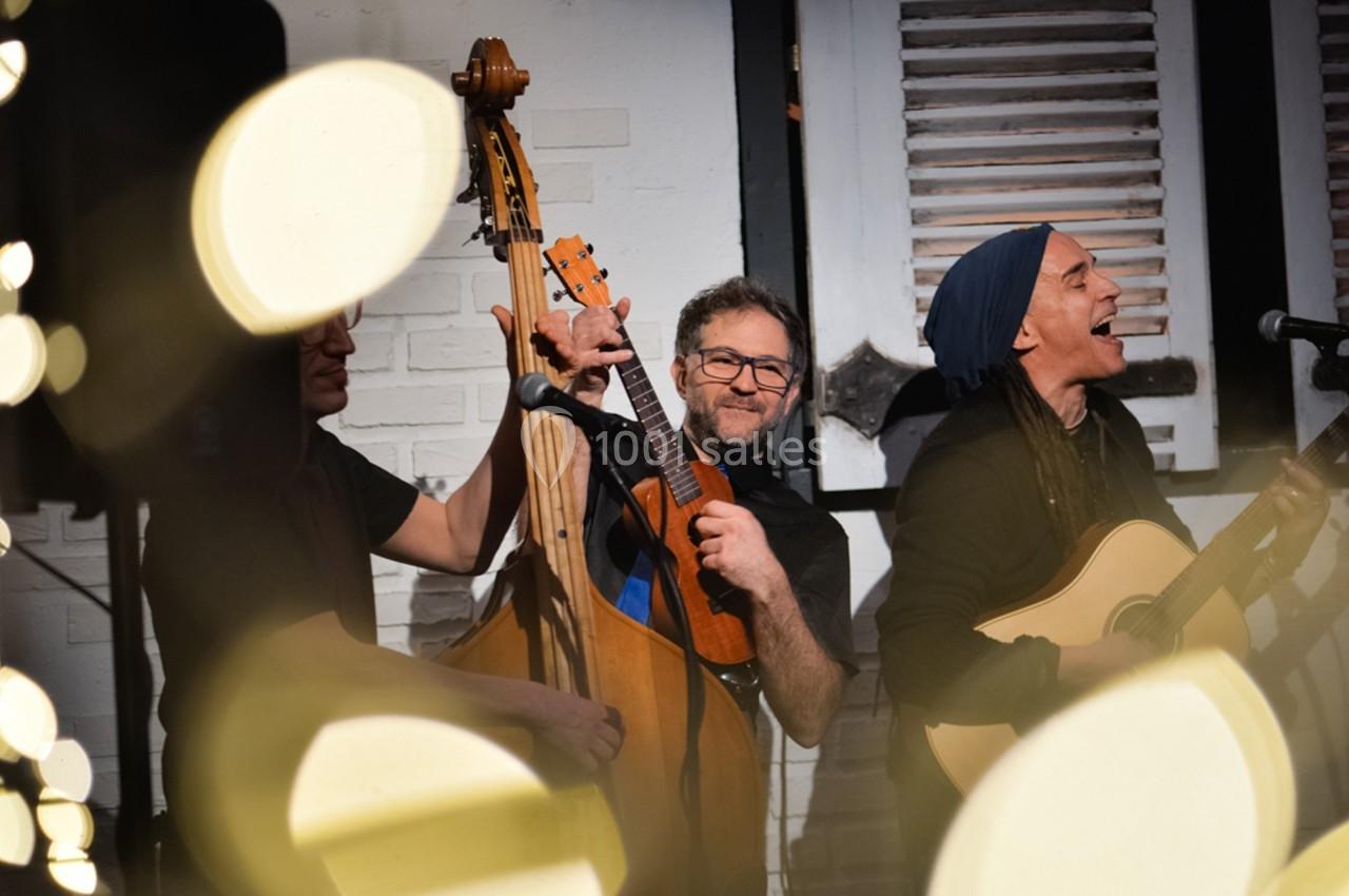 Musiciens jouant de la contrebasse et de la guitare dans une ambiance chaleureuse avec des lumières floues au premier plan.