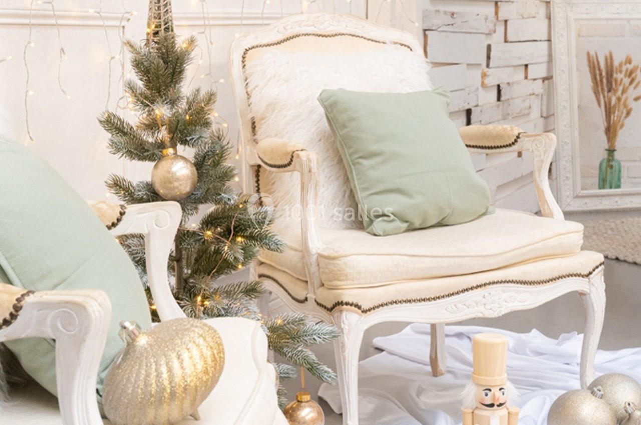 Fauteuils anciens avec coussins verts, sapin décoré de boules dorées et casse-noisette dans un décor lumineux et festif.