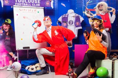 Miniature Studio le Carré #4 Femme portant des lunettes en forme de cœur jouant de la guitare électrique dans un décor rétro avec objets dorés.