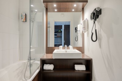 Serviettes blanches roulées posées sur un lit avec des oreillers et des draps blancs en arrière-plan.