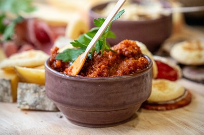 Serviettes blanches roulées posées sur un lit avec des oreillers et des draps blancs en arrière-plan.