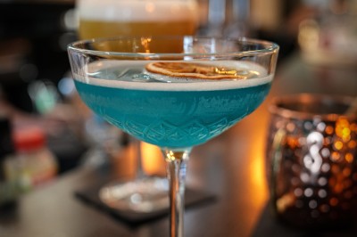 Serviettes blanches roulées posées sur un lit avec des oreillers et des draps blancs en arrière-plan.