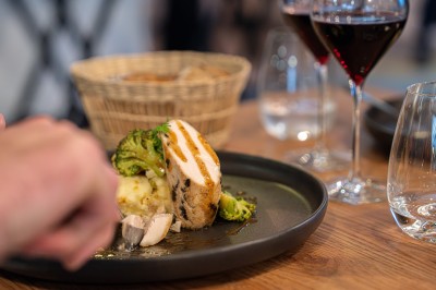Serviettes blanches roulées posées sur un lit avec des oreillers et des draps blancs en arrière-plan.
