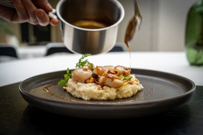 Serviettes blanches roulées posées sur un lit avec des oreillers et des draps blancs en arrière-plan.