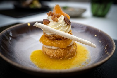 Serviettes blanches roulées posées sur un lit avec des oreillers et des draps blancs en arrière-plan.