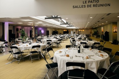 Serviettes blanches roulées posées sur un lit avec des oreillers et des draps blancs en arrière-plan.