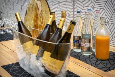 Serviettes blanches roulées posées sur un lit avec des oreillers et des draps blancs en arrière-plan.