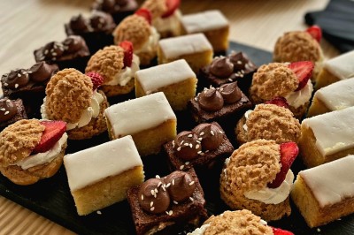 Serviettes blanches roulées posées sur un lit avec des oreillers et des draps blancs en arrière-plan.