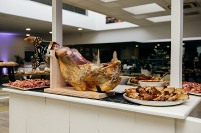 Serviettes blanches roulées posées sur un lit avec des oreillers et des draps blancs en arrière-plan.