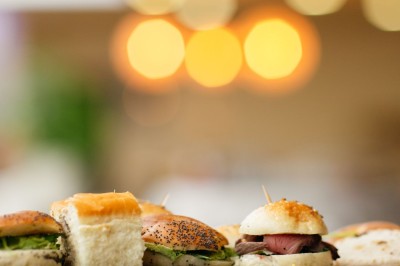 Serviettes blanches roulées posées sur un lit avec des oreillers et des draps blancs en arrière-plan.