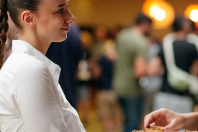 Serviettes blanches roulées posées sur un lit avec des oreillers et des draps blancs en arrière-plan.