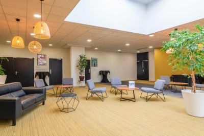 Serviettes blanches roulées posées sur un lit avec des oreillers et des draps blancs en arrière-plan.