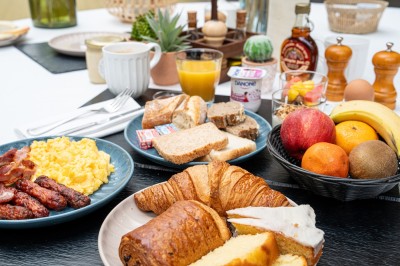 Serviettes blanches roulées posées sur un lit avec des oreillers et des draps blancs en arrière-plan.