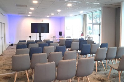 Serviettes blanches roulées posées sur un lit avec des oreillers et des draps blancs en arrière-plan.