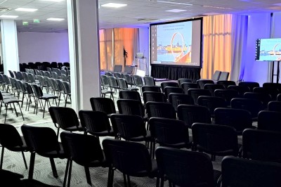 Serviettes blanches roulées posées sur un lit avec des oreillers et des draps blancs en arrière-plan.