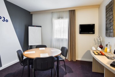 Serviettes blanches roulées posées sur un lit avec des oreillers et des draps blancs en arrière-plan.