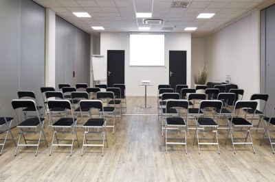 Serviettes blanches roulées posées sur un lit avec des oreillers et des draps blancs en arrière-plan.